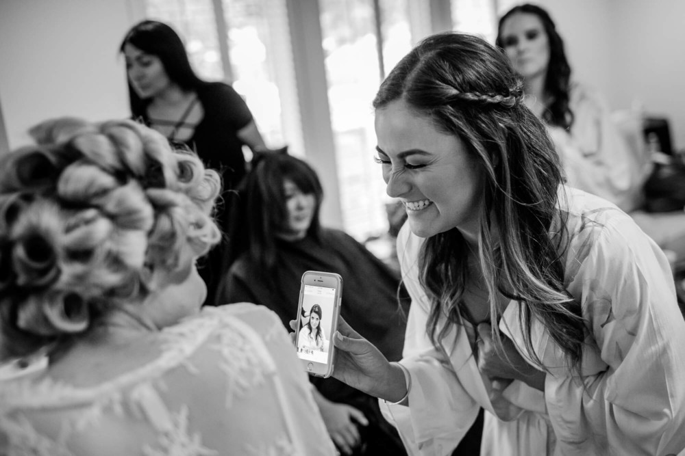 Bridesmaid showing bride funny picture her phone