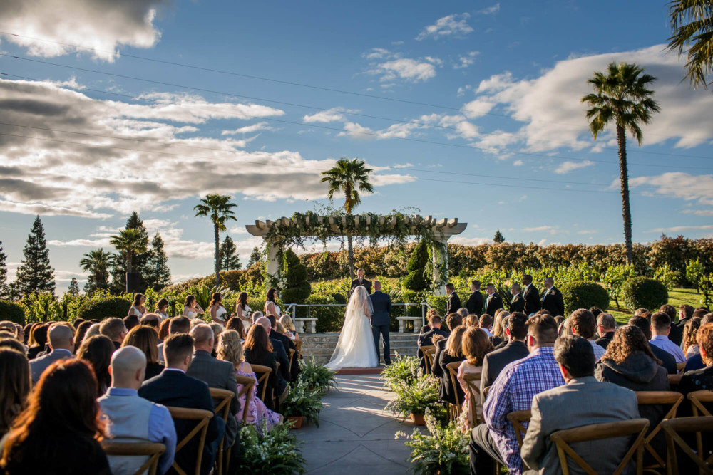 wide shot of the wedding ceremony overlooking a vineyard