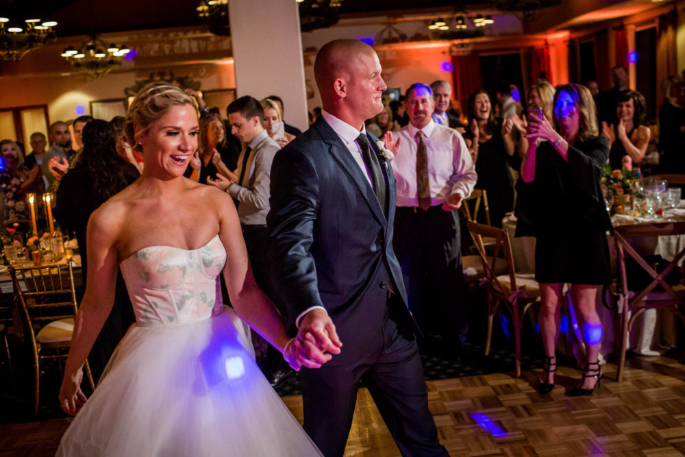 Bride and groom enter the reception under colorful lights