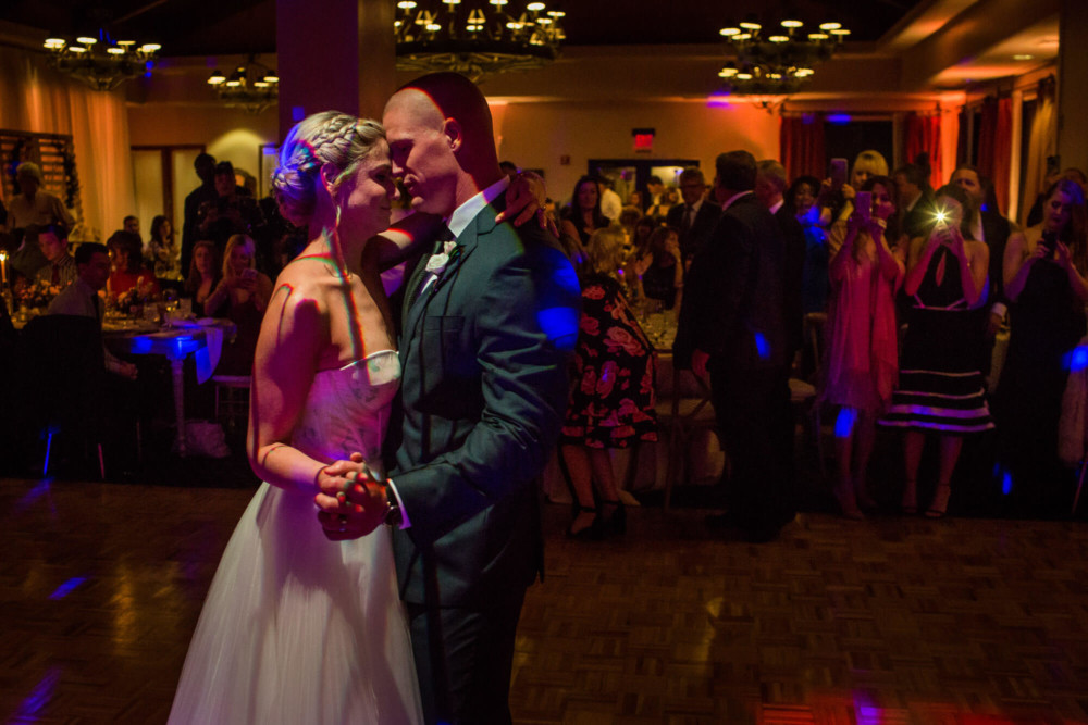 bride and groom have the first dance under colorful dance lights