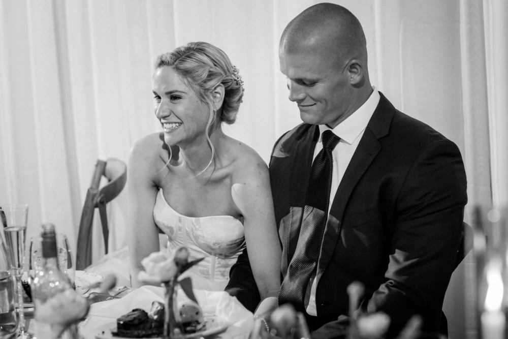 Bride and groom laugh during the speeches at their wedding reception