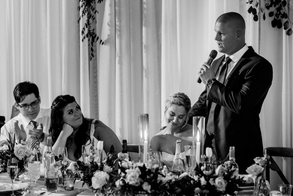 Groom gives speech at his wedding reception while holding the bride