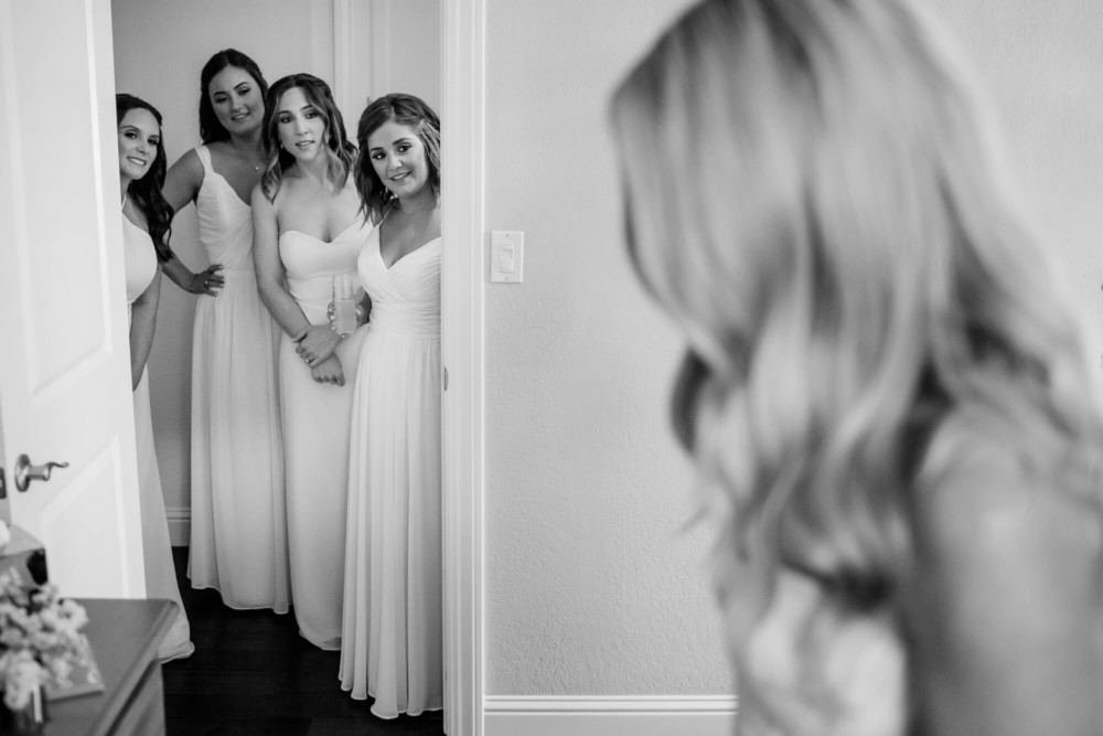 bridesmaids looking at the bride in her dress while getting ready