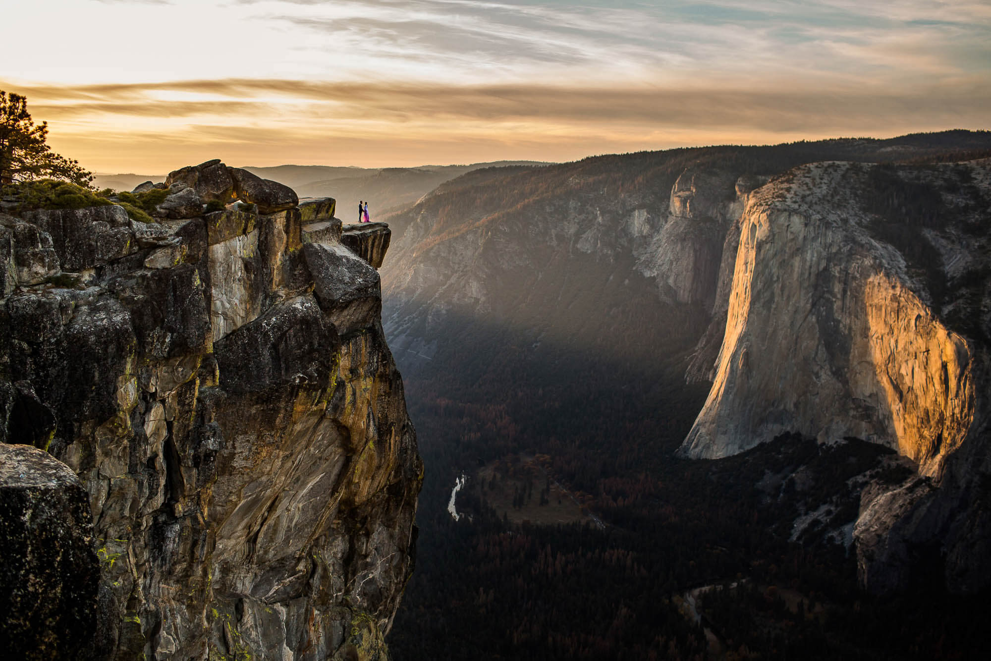 Couple standing on ledge during their wedding at Taft Point looking over Yosemite Valley