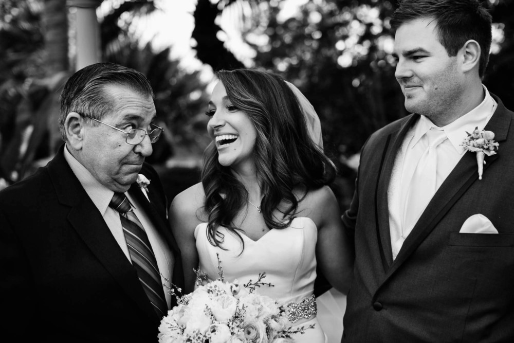 Father of the bride gives the bride a funny look while the groom looks on