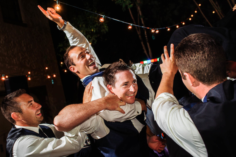 Groomsmen carrying another during dancing at a wedding reception