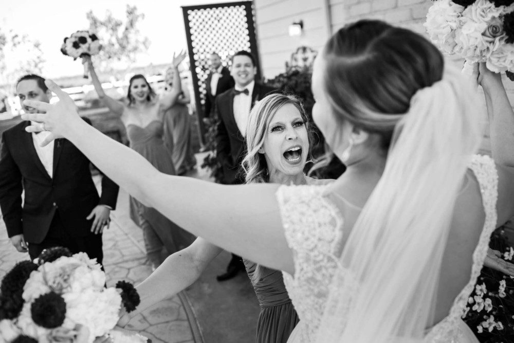 Bridesmaid and bride run towards each other with their arms raised