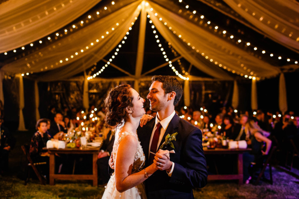 Bride and groom sharing their first dance under the lights in a clear tent at their wedding reception