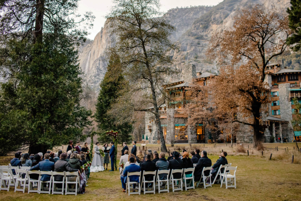 Ceremony on the wedding lawn at the Majestic Yosemite Hotel with Yosemite Falls in the background