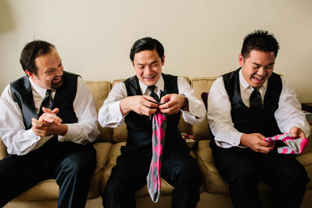 Groom and groomsmen putting on crazy colored socks