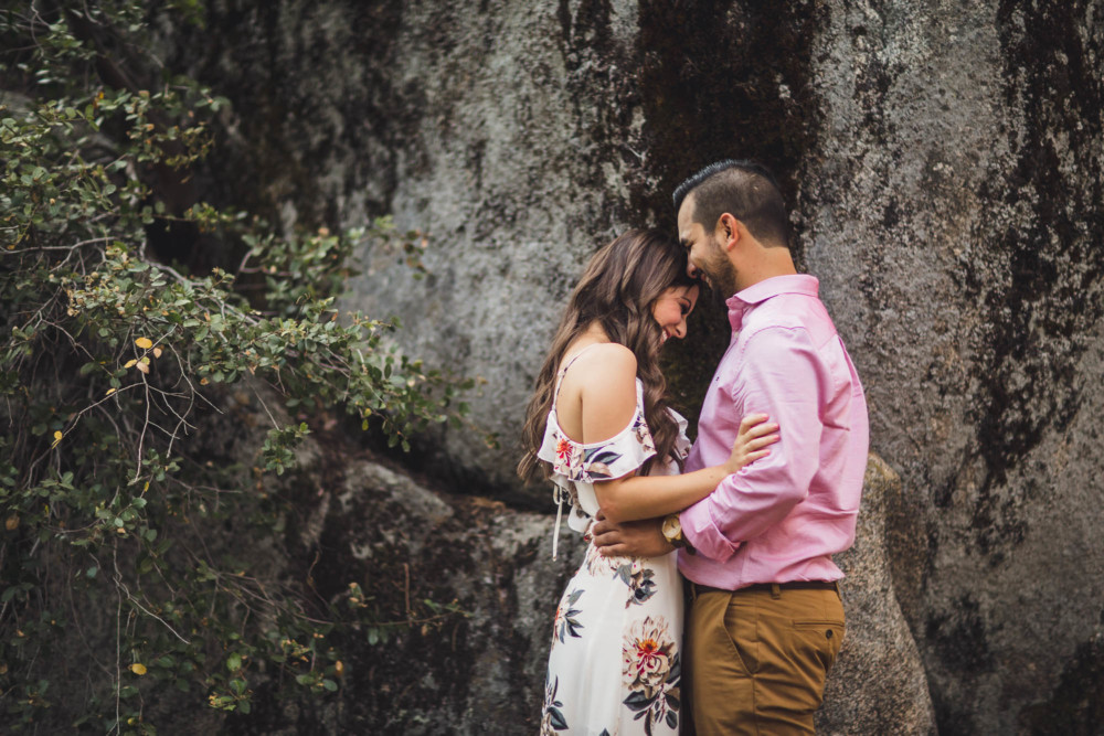 A couple shares a funny moment in front of a granite wall