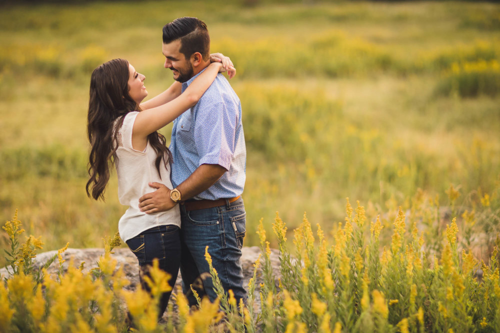 Couple looking at each other in a meadow full of yellow flowers