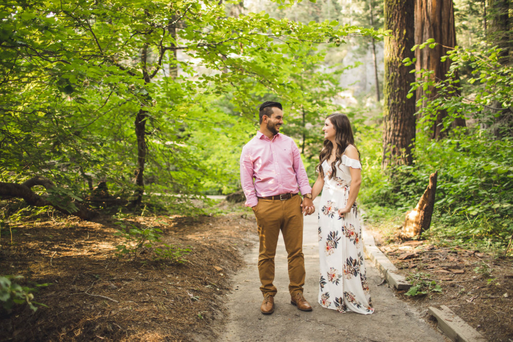 Couple walks along the trail and laughs in a redwood grove