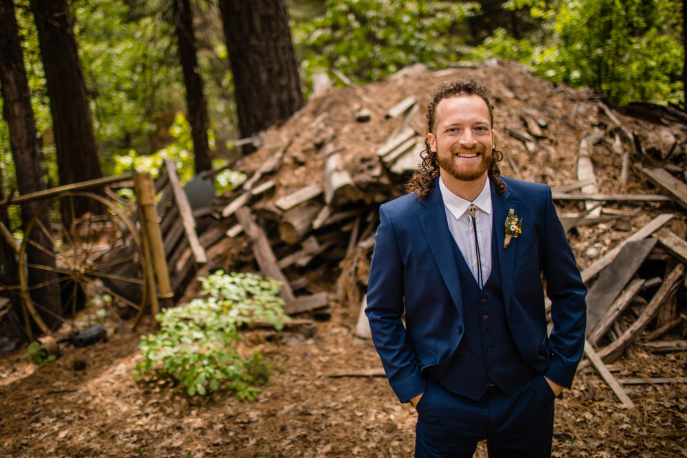 Portrait of groom in front of a woodpile