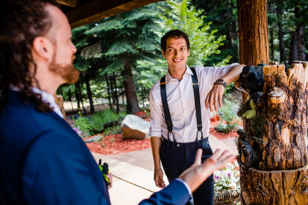 Groomsman holding a drink laughs at a story told by the groom