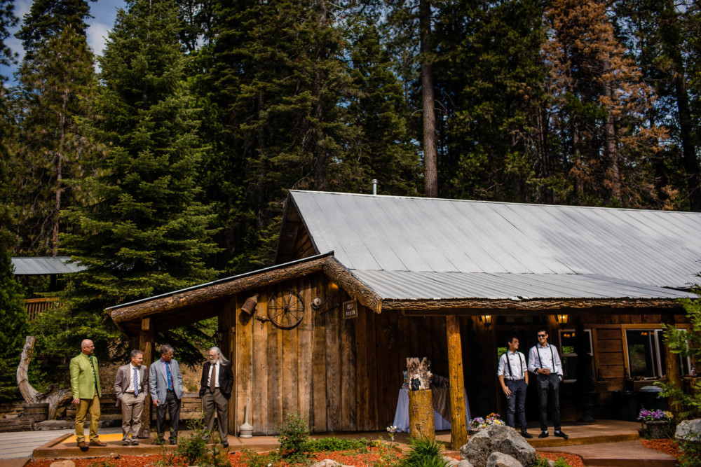 Groomsmen gather and talk on the porch of a cabin
