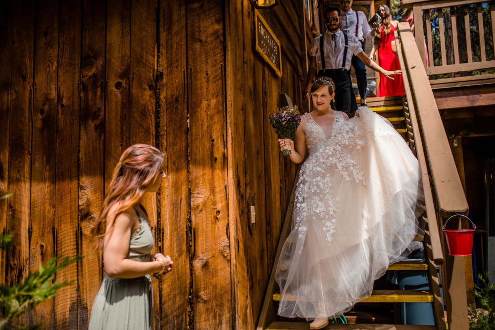Bride coming down stairs while bridesmaid waits at the bottom