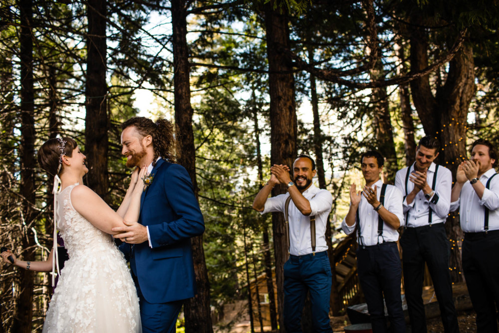 Groomsmen clap after the bride and groom share their first kiss