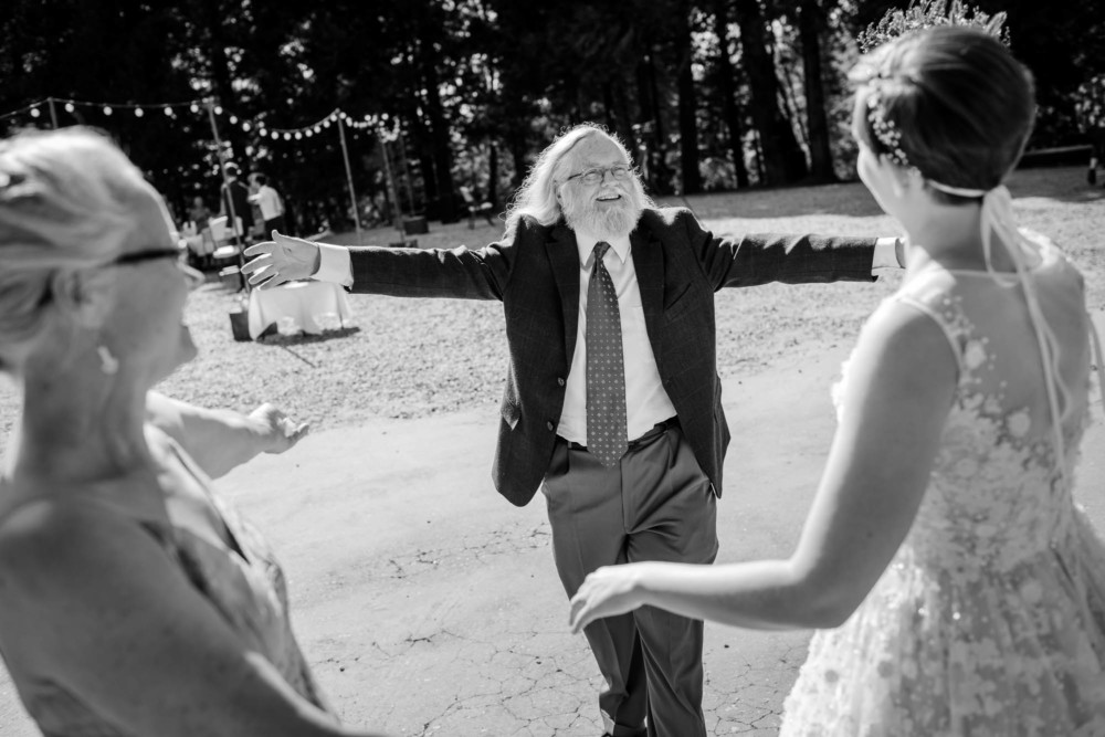 Father of the bride walks towards the bride with his arms outstretched