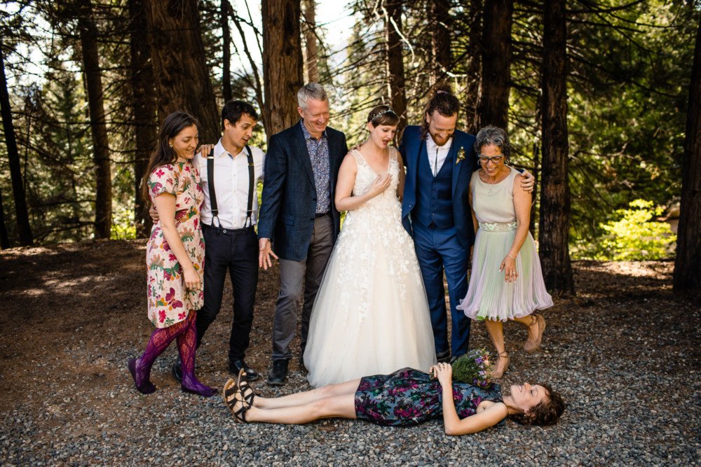 Sister of the groom lays down and plays dead during the family portraits