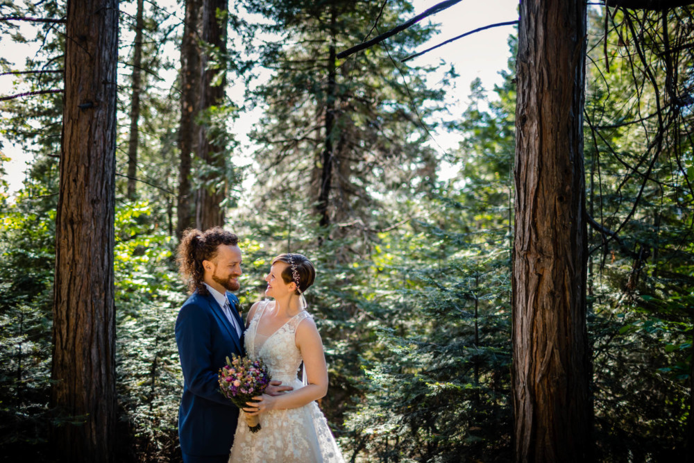 Bride and groom pose for a romantic portrait in the forest near Yosemite National Park