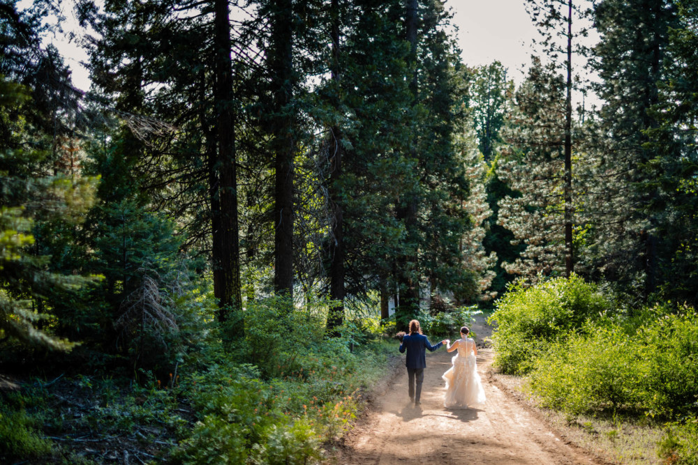 Bride and groom walk down a trail in the mountains after their wedding ceremony at Paradise Springs