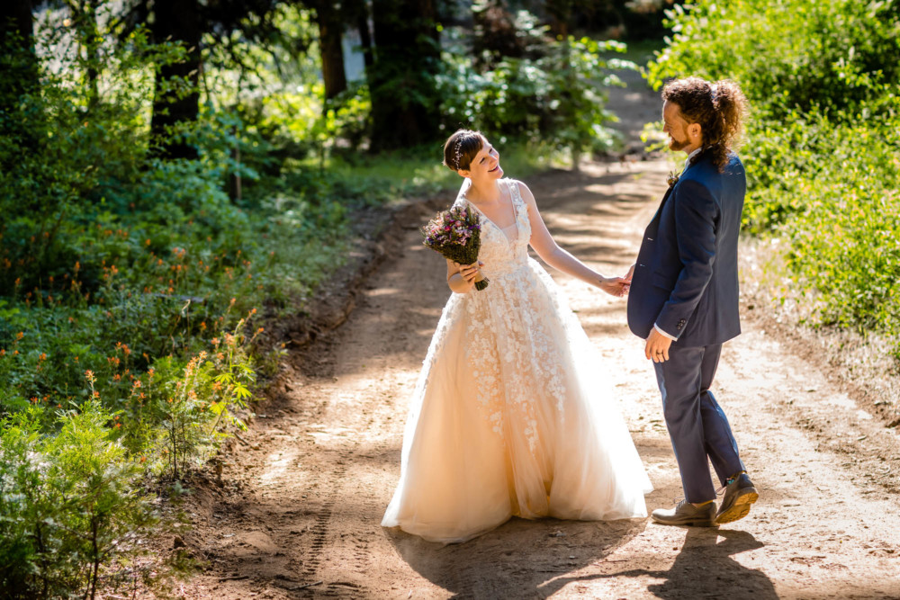 Bride and groom laugh together on the trail in the forest