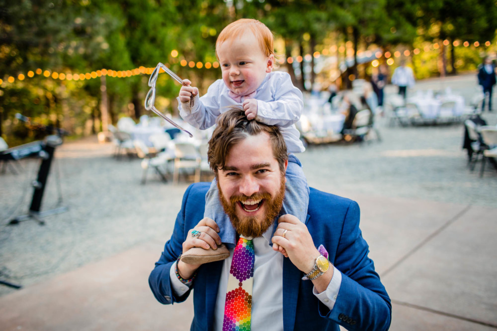 Toddler rides dads shoulders during a wedding reception
