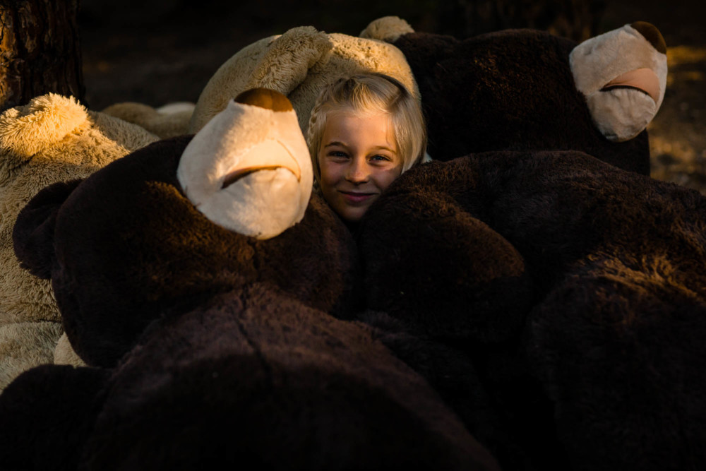 Little girl hides in pile of giant teddy bears