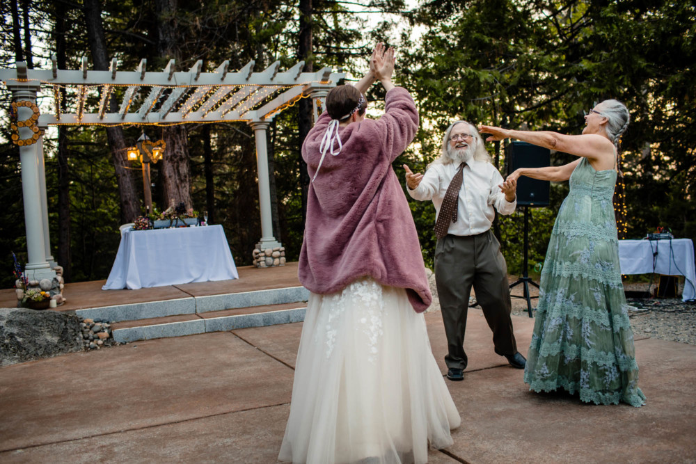 Father and mother dance with their daughter the bride during the wedding reception in the forest