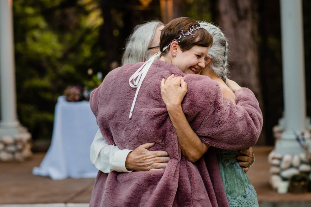 Bride hugs her mom and dad at the end of the father daughter dance