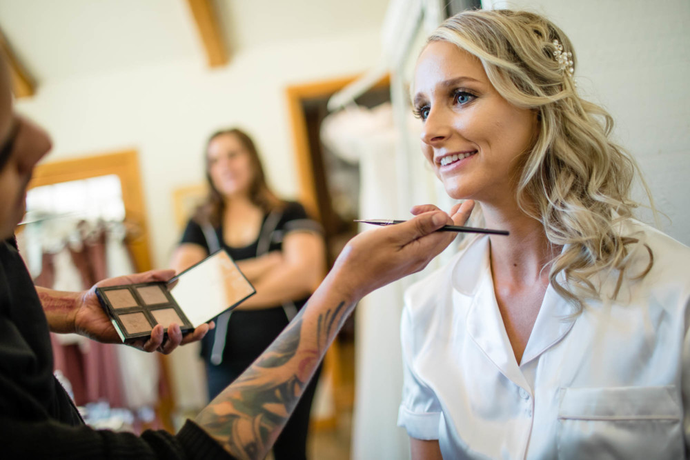 Make up artist raises the brides chin while doing her makeup before the wedding.