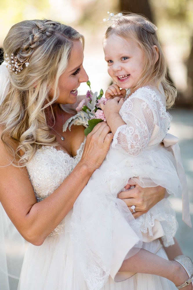 bride tickles her toddler flower girl
