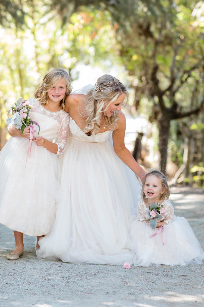 Bride laughing and playing with her flowergirls all dressed in white