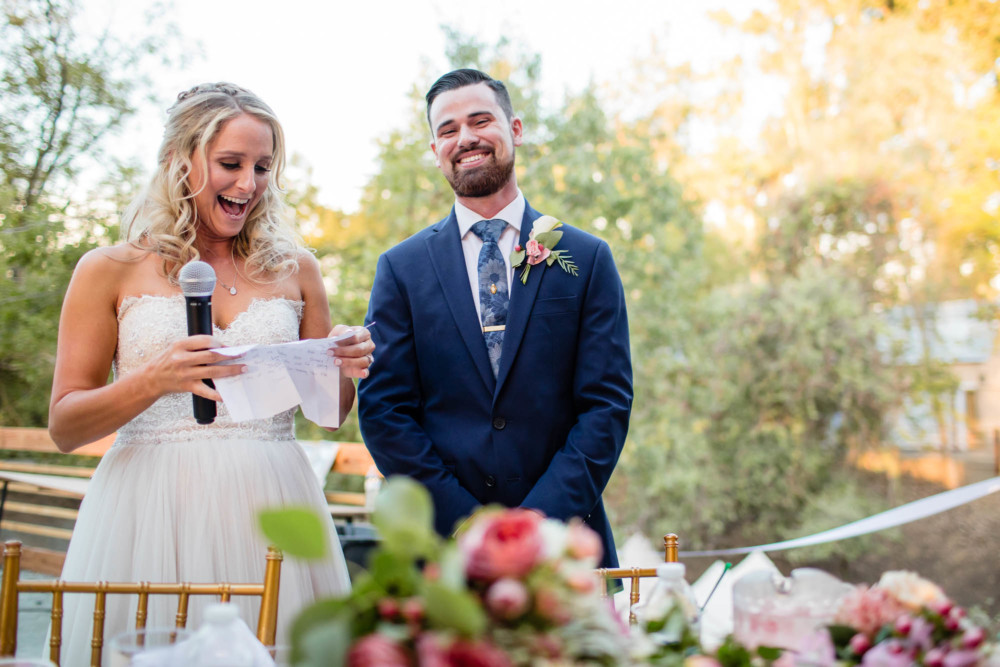 Bride and groom laugh during their speech at their wedding reception
