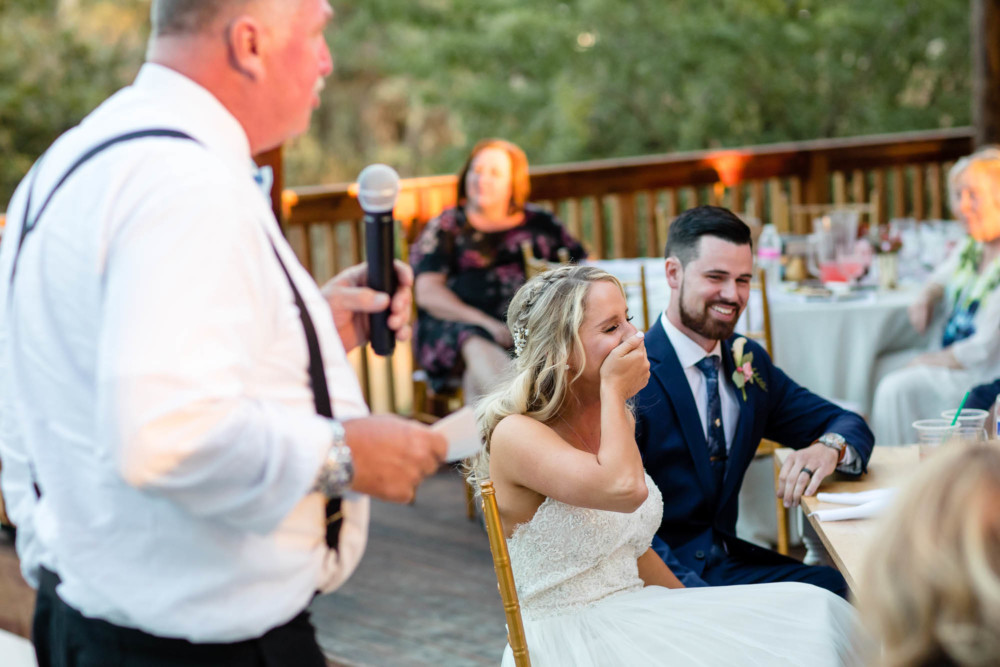 Bride laughs at a joke told by her father during his speech at a wedding reception