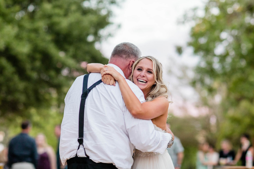 Bride laughs as she dances with her father at her wedding reception