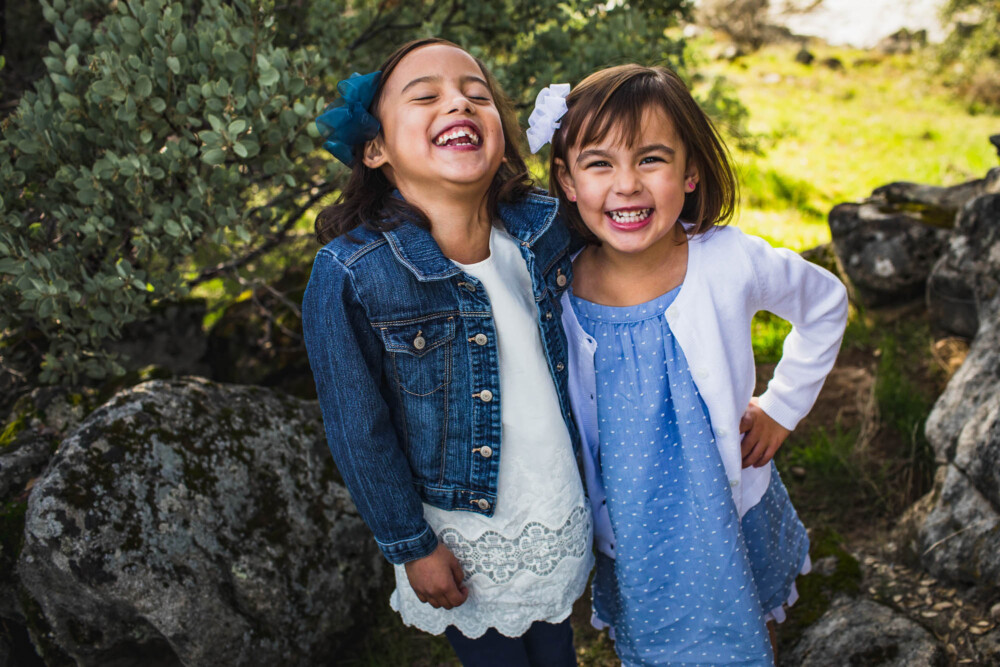 Two sisters laugh during their outdoor family portrait session in the mountains