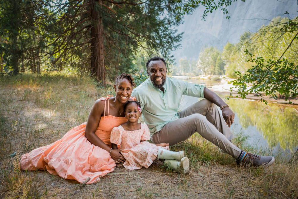 Family poses next to a river for a family portrait session in the mountains