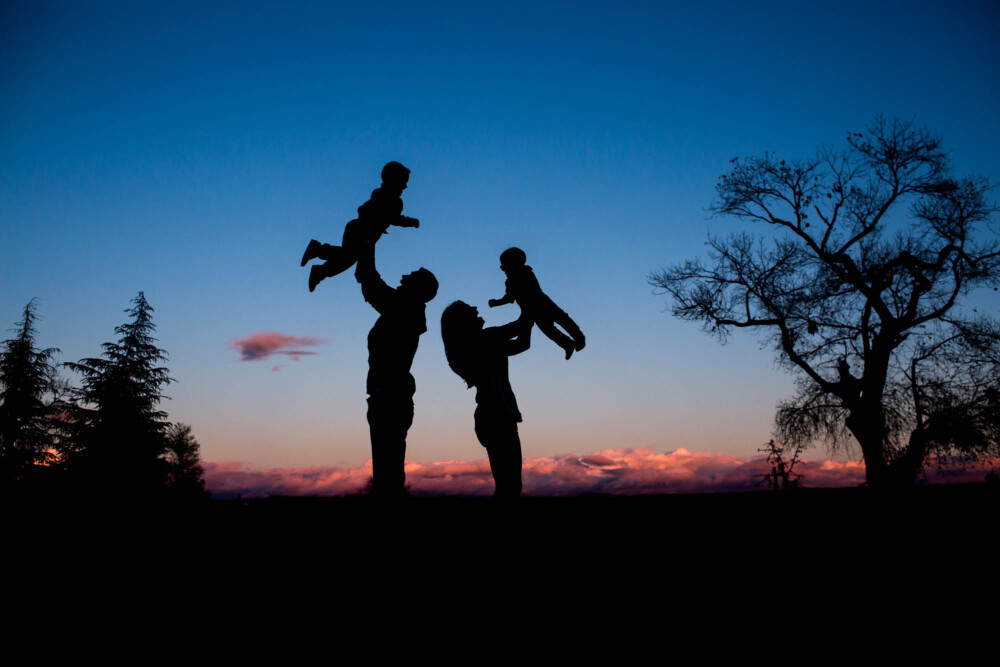 silhouette of mom and dad tossing their small boys into the air